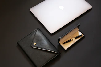 silver macbook beside black leather wallet