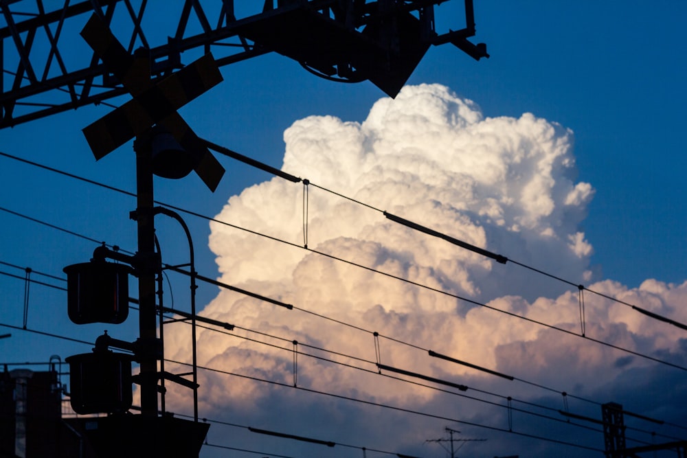 black electric post under blue sky and white clouds during daytime