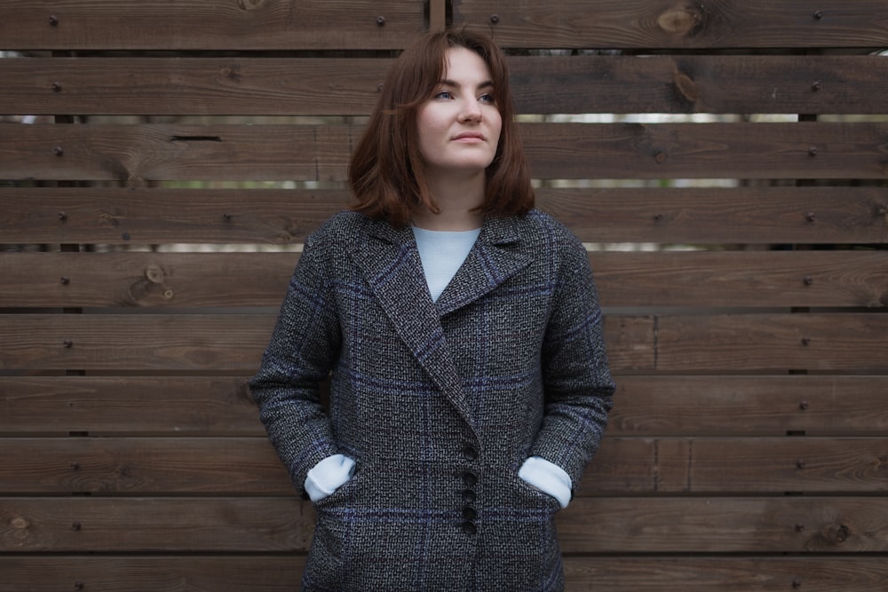 woman in blue and white polka dot coat standing near brown wooden wall