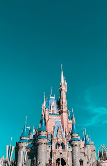 A vibrant Minecraft castle built with detailed stone and wood textures under a bright blue sky.