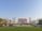 A large red brick building is seen in the center, flanked by rows of trees and a neatly manicured lawn in the foreground. Several workers in uniform are gathered near vehicles and are possibly engaging in landscaping activities. The letters 'Chengdu University' are prominently displayed on the lawn in front.