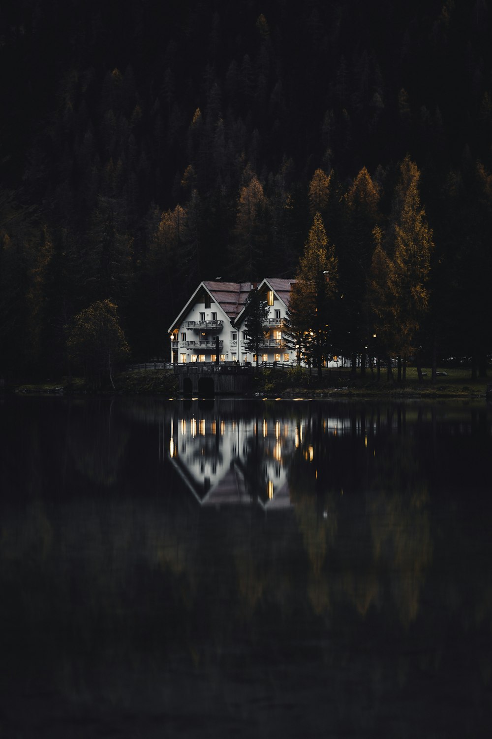 Weißes und braunes Haus in Seenähe, umgeben von Bäumen