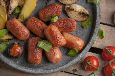 A sizzling plate of saslyk with fresh herbs and grilled vegetables on a rustic wooden table.