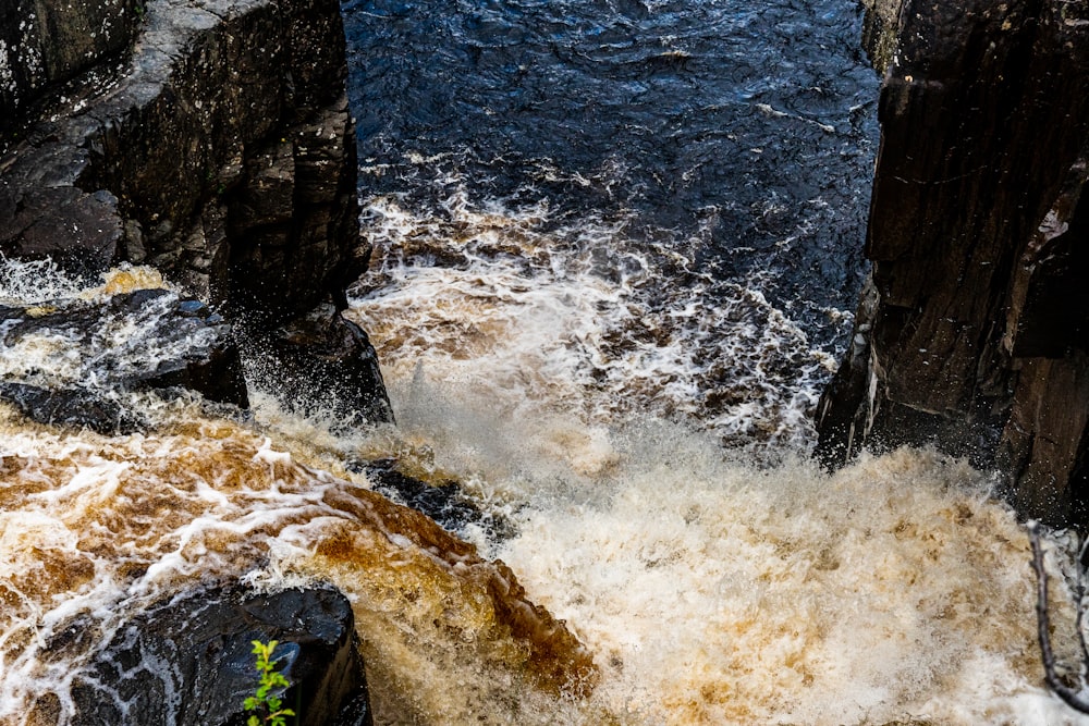 water waves hitting rock formation during daytime