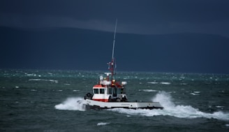 An oil tanker navigating through turbulent sea waters under dark storm clouds.