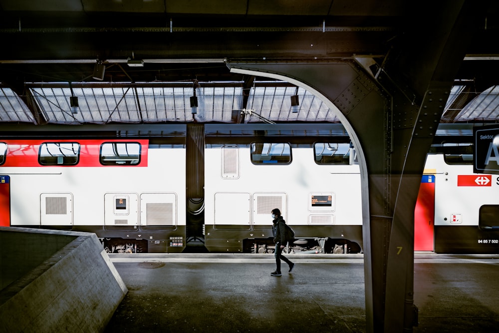 homme en veste noire marchant près d’un train blanc