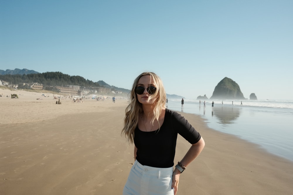 woman in black shirt and white skirt standing on beach during daytime