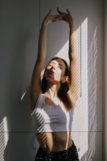 woman in white tank top standing beside white wall