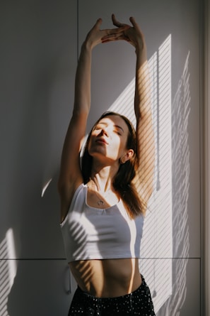 woman in white tank top standing beside white wall