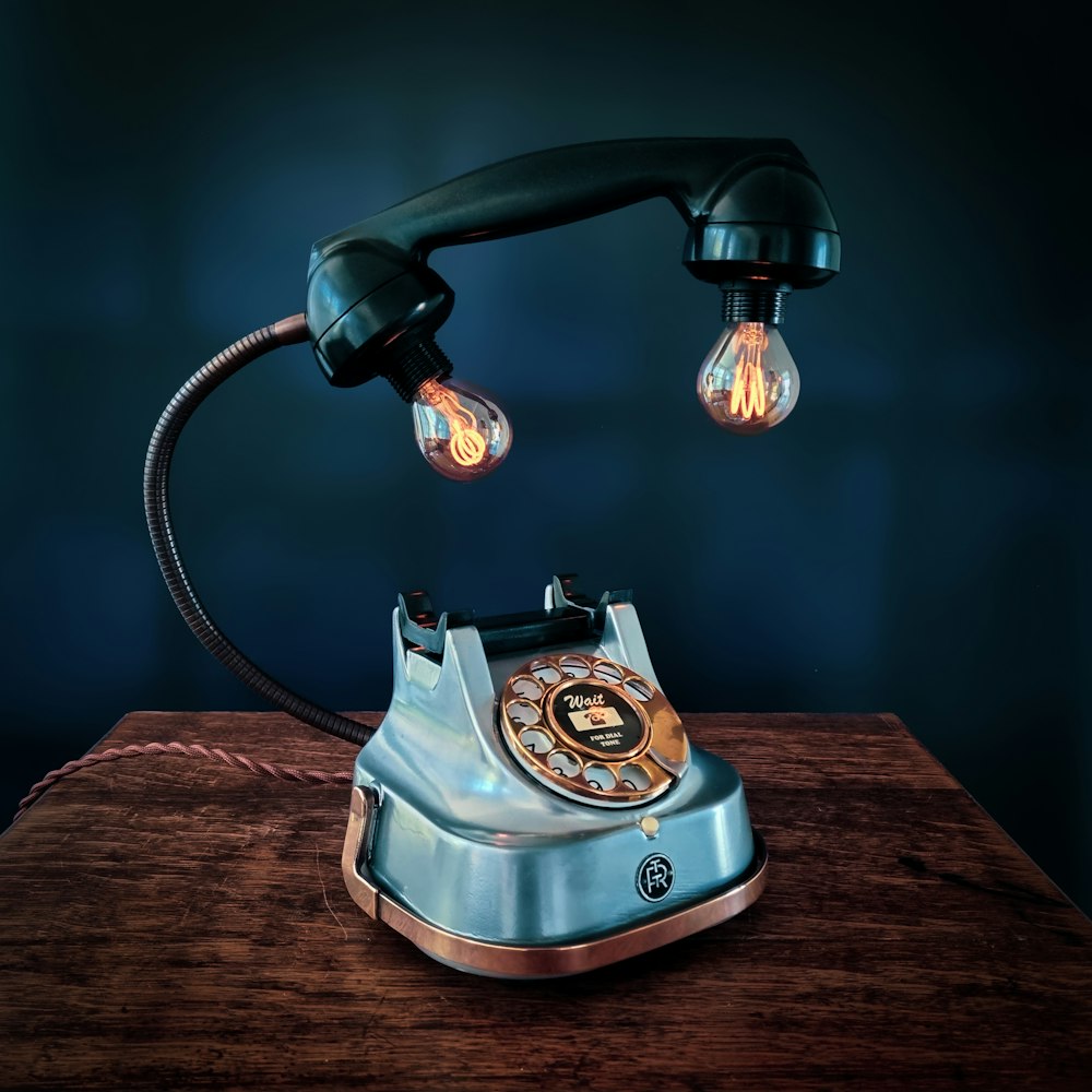 black and silver rotary phone on brown wooden table