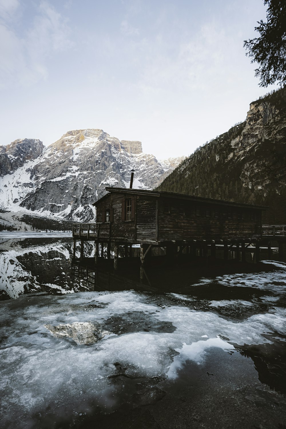 brown wooden house on snow covered ground near mountain during daytime