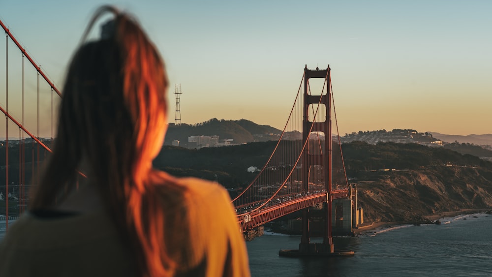 woman standing on bridge during sunset