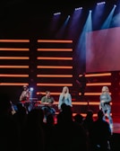 A group of musicians performing on stage with vibrant lights.