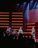 Band performing live on stage with red and black lighting.