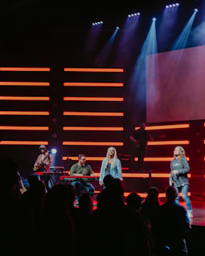 A vibrant group of young musicians performing passionately on stage under green and red lights.