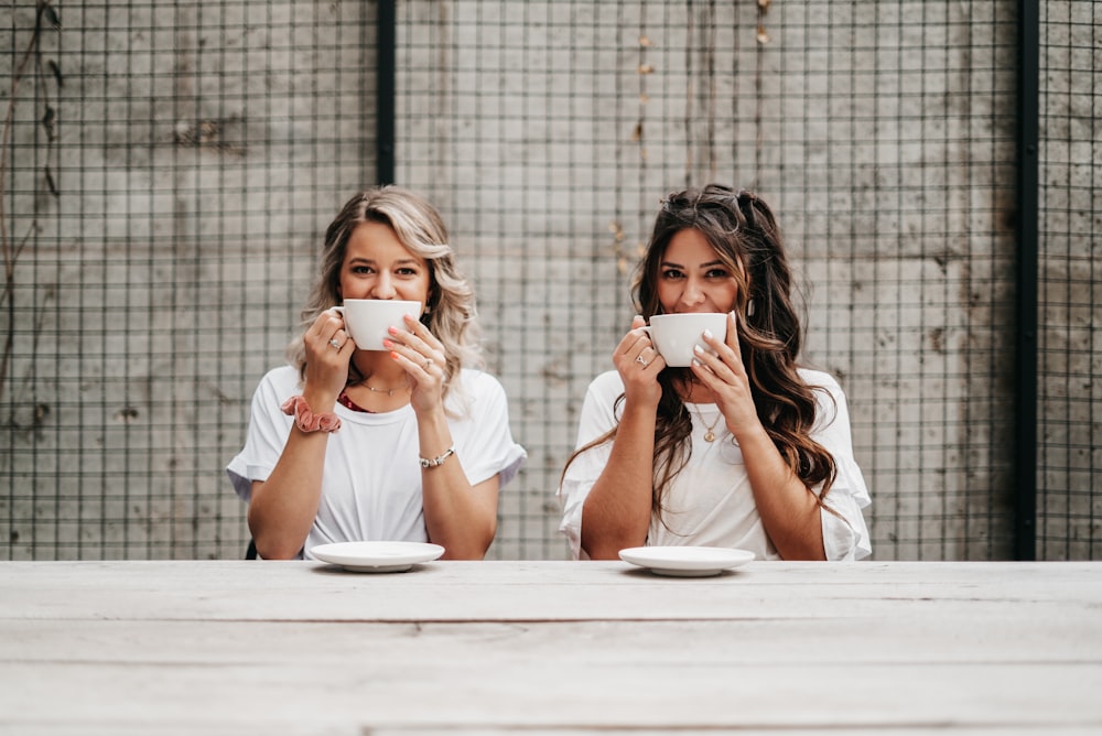 woman in white shirt drinking from white ceramic mug