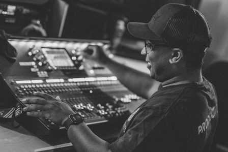 man in black hat and black shirt using audio mixer