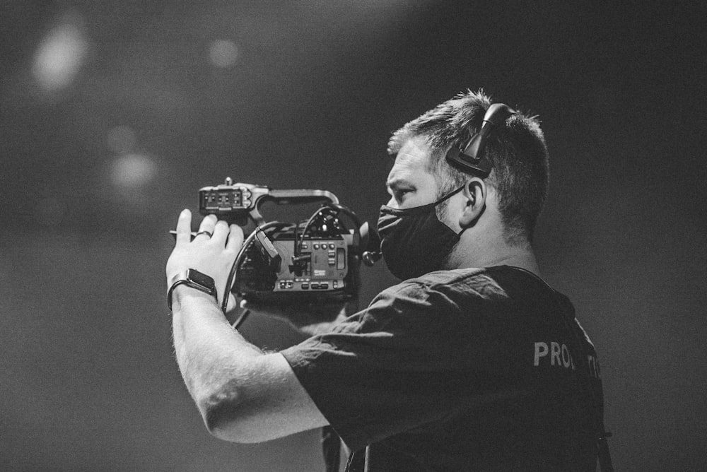 homem na camiseta preta do pescoço da tripulação segurando a câmera dslr preta