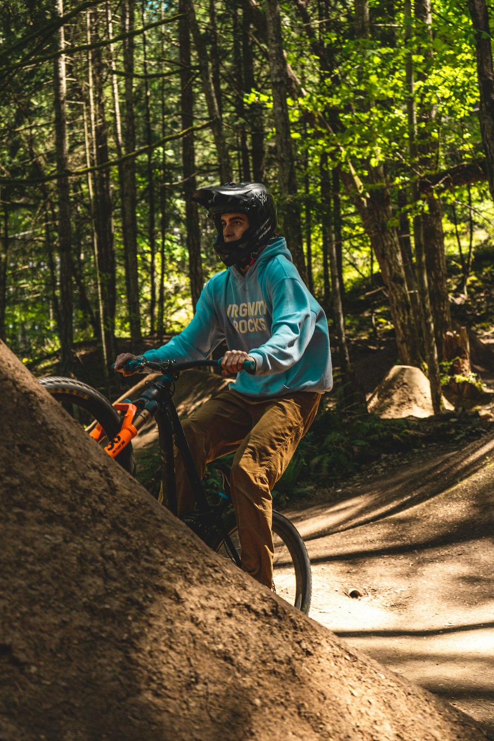 man in blue dress shirt and brown pants riding bicycle on brown rock formation during daytime