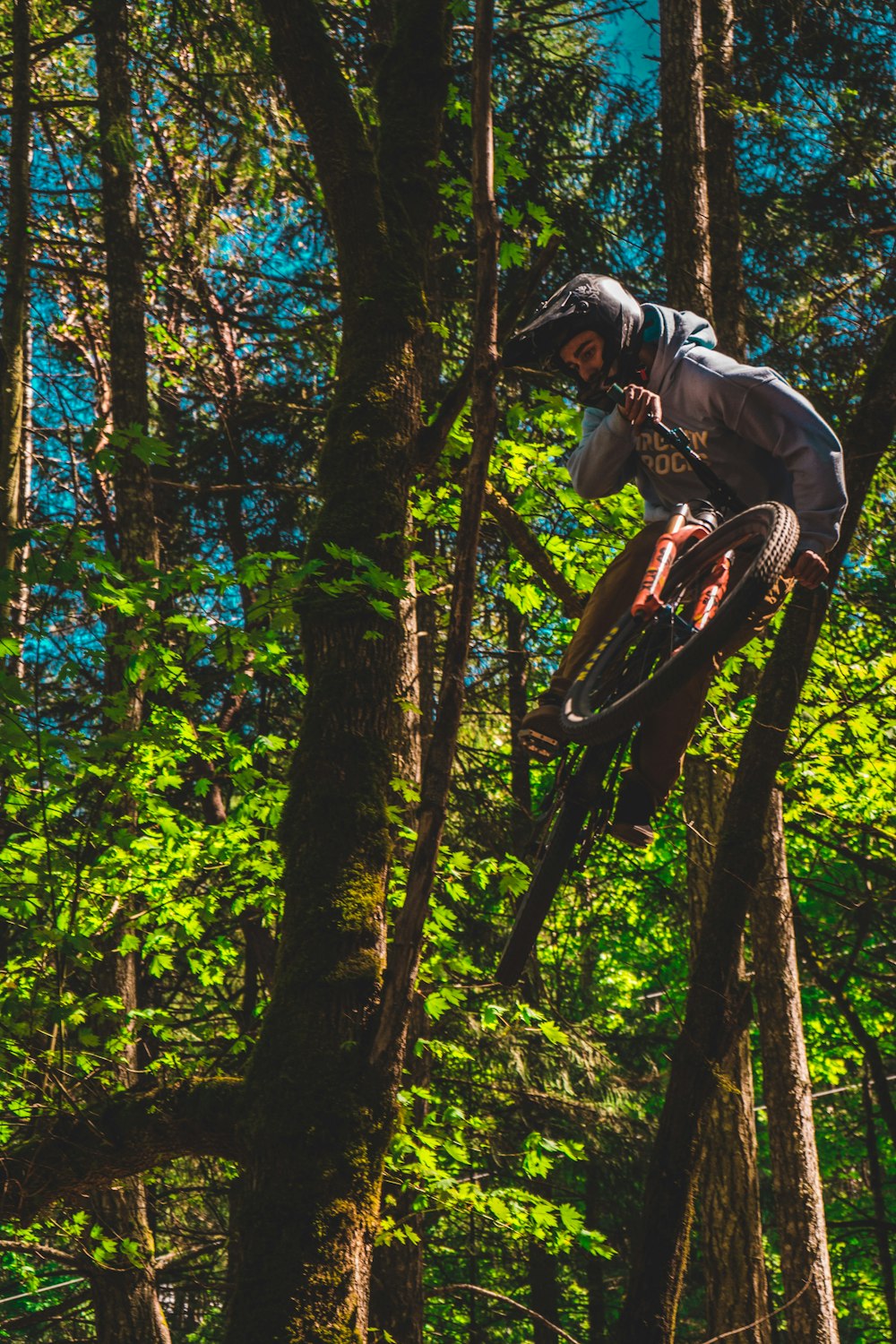 man in gray jacket riding on bicycle in forest during daytime