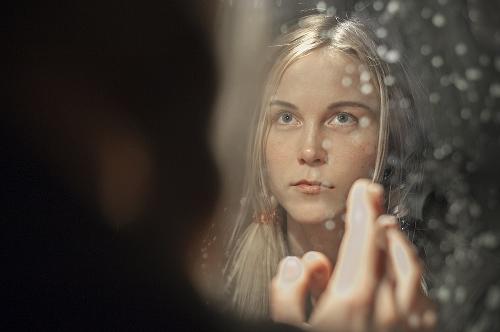 woman with blonde hair holding her face