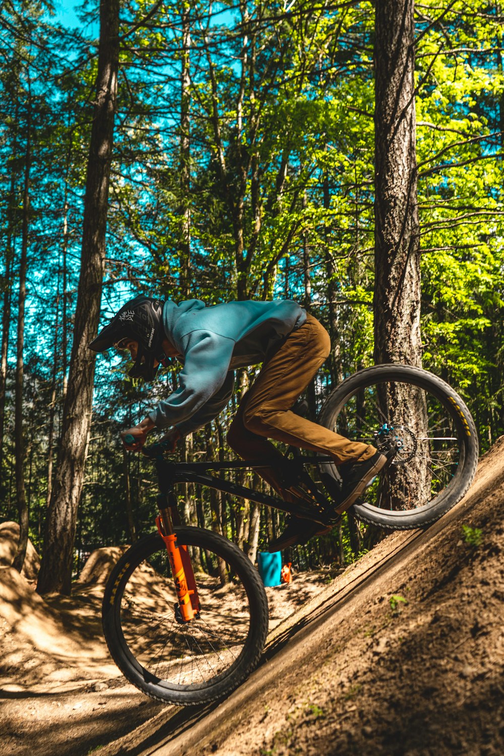 man in gray long sleeve shirt riding bicycle on forest during daytime