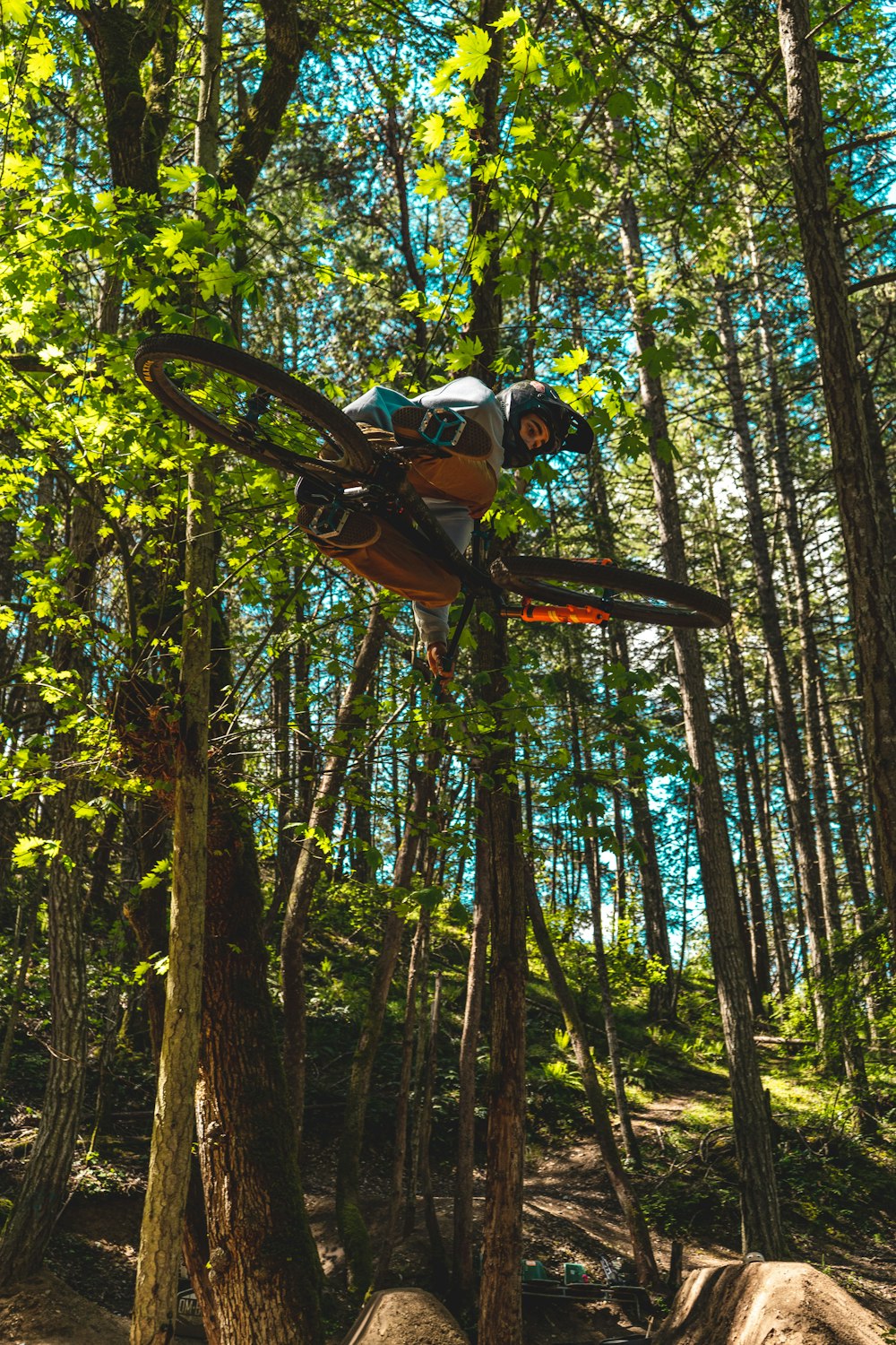 man in orange jacket riding on orange and black bicycle in forest during daytime