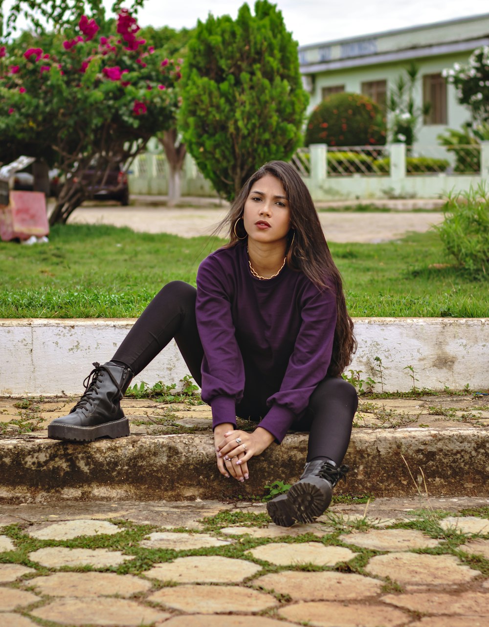 woman in purple long sleeve shirt and black pants sitting on brown concrete bench during daytime