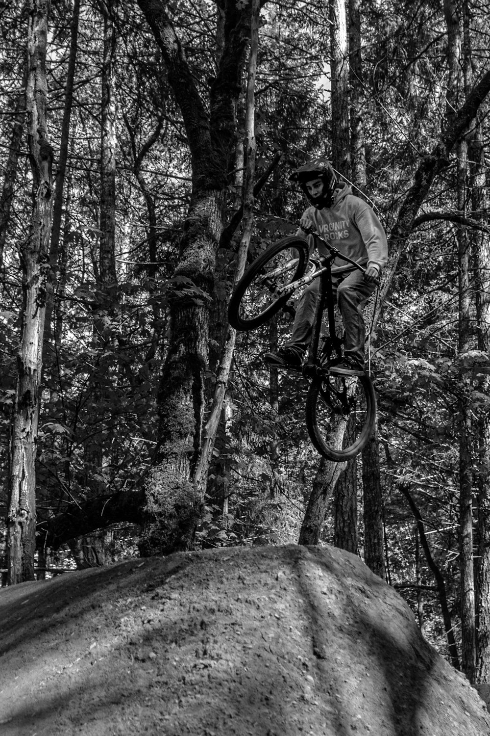 grayscale photo of man riding bicycle on rocky mountain