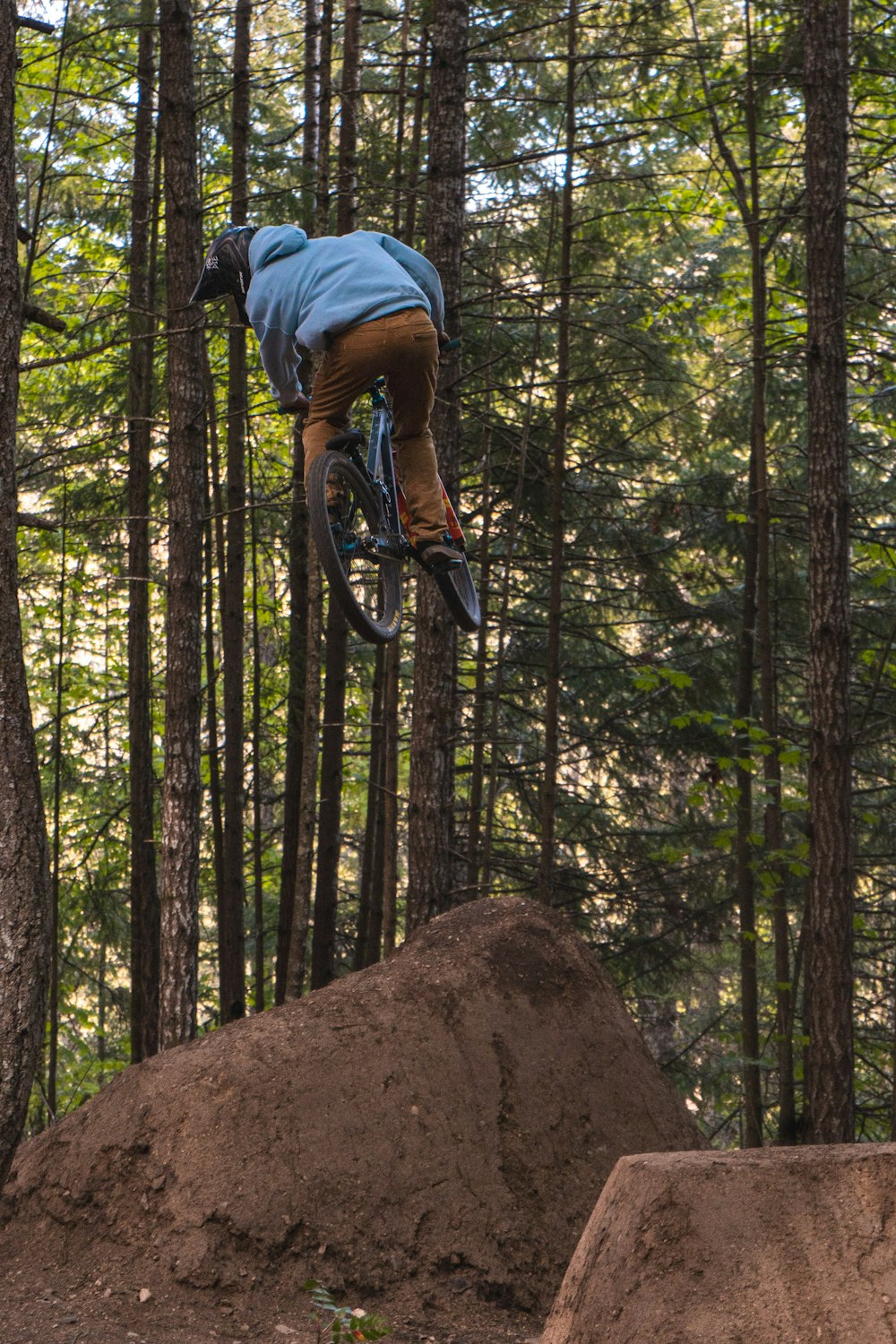 man in blue jacket riding bicycle in forest during daytime