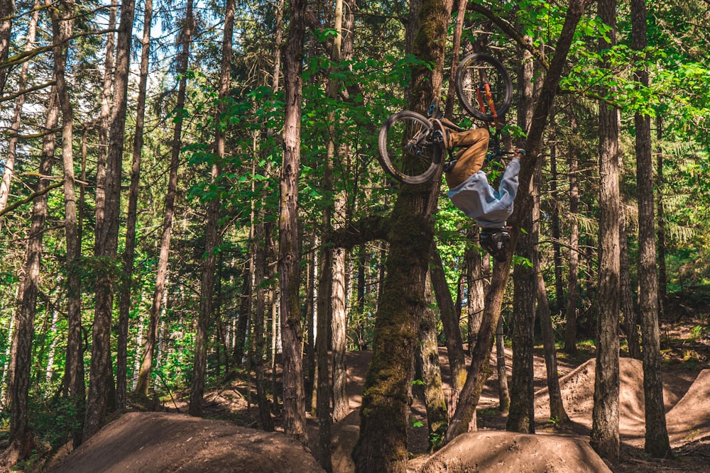 man in blue long sleeve shirt riding on bicycle in forest during daytime