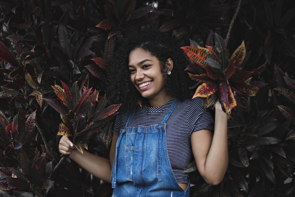 woman in blue denim vest standing near red leaves