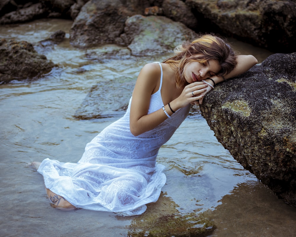 woman in blue dress lying on rock by the sea