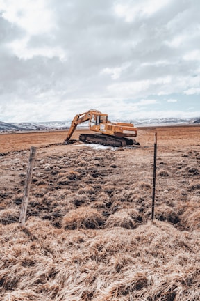 A technician inspecting earth moving equipment in a field.