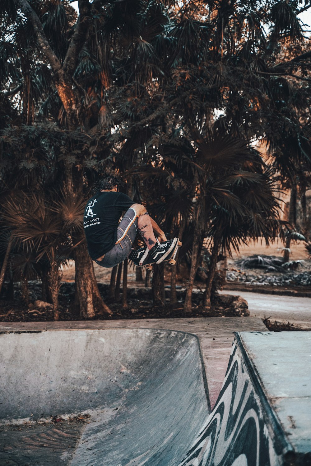 homme en veste noire et blanche et jean bleu assis sur un banc en béton