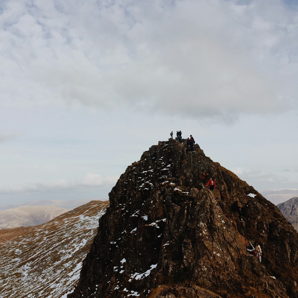 person standing on rock formation under white clouds during daytime