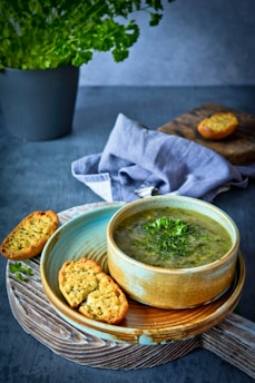 Steaming bowl of hearty moringa soup with fresh herbs on a wooden table