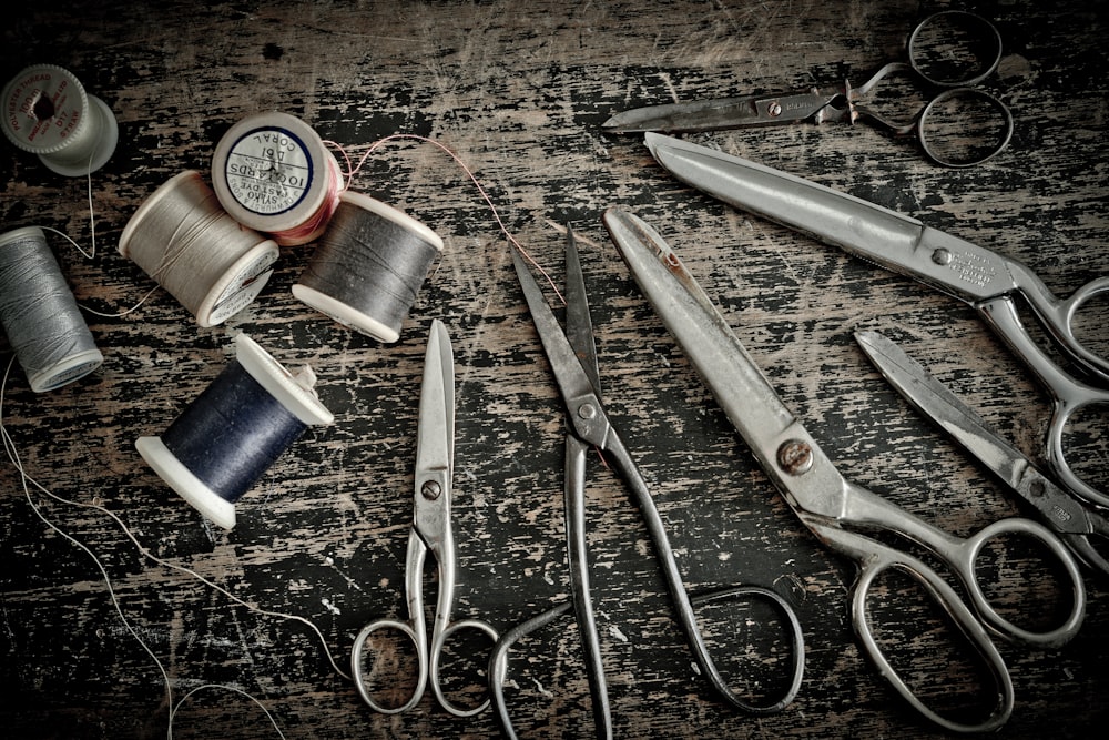 stainless steel scissors beside blue thread