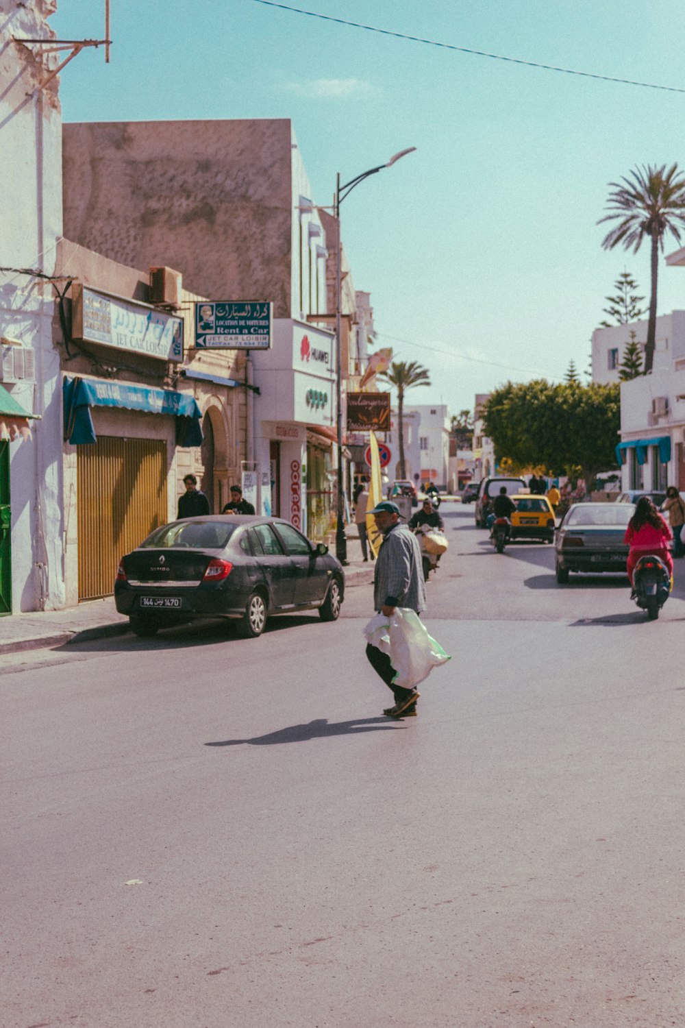 man in white shirt walking on sidewalk during daytime