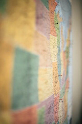 A map with various colored regions, each marked with small pins. The map is slightly out of focus, providing a soft and blended appearance to the colors.