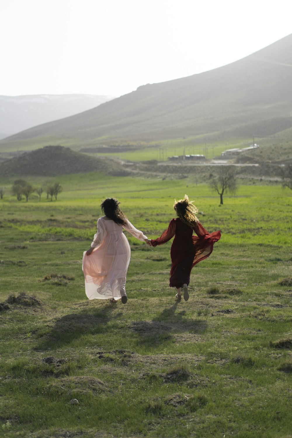 woman in white dress holding man in red robe on green grass field during daytime
