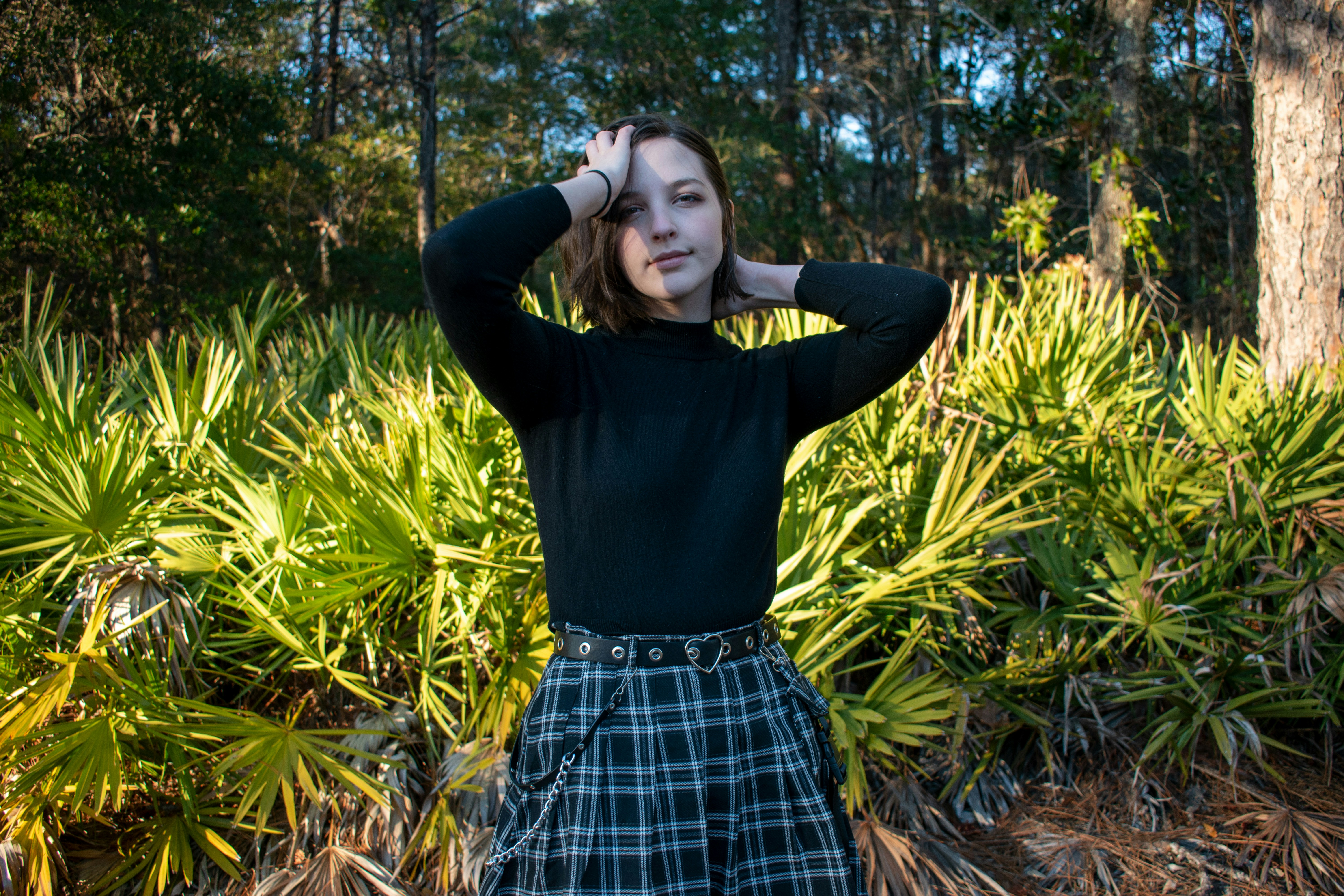 woman in black long sleeve shirt and blue and white plaid skirt…