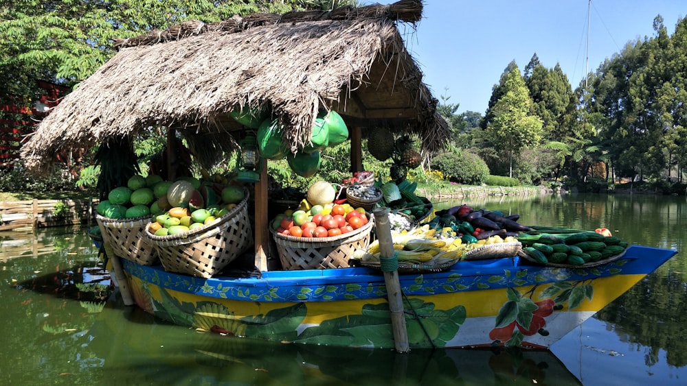 Cabaña de nipa marrón rodeada de frutas en un bote de madera verde en el agua