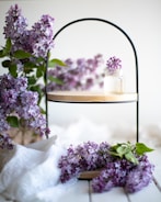 Display of delicate, feminine decorative pieces arranged on a wooden shelf with lilac accents.