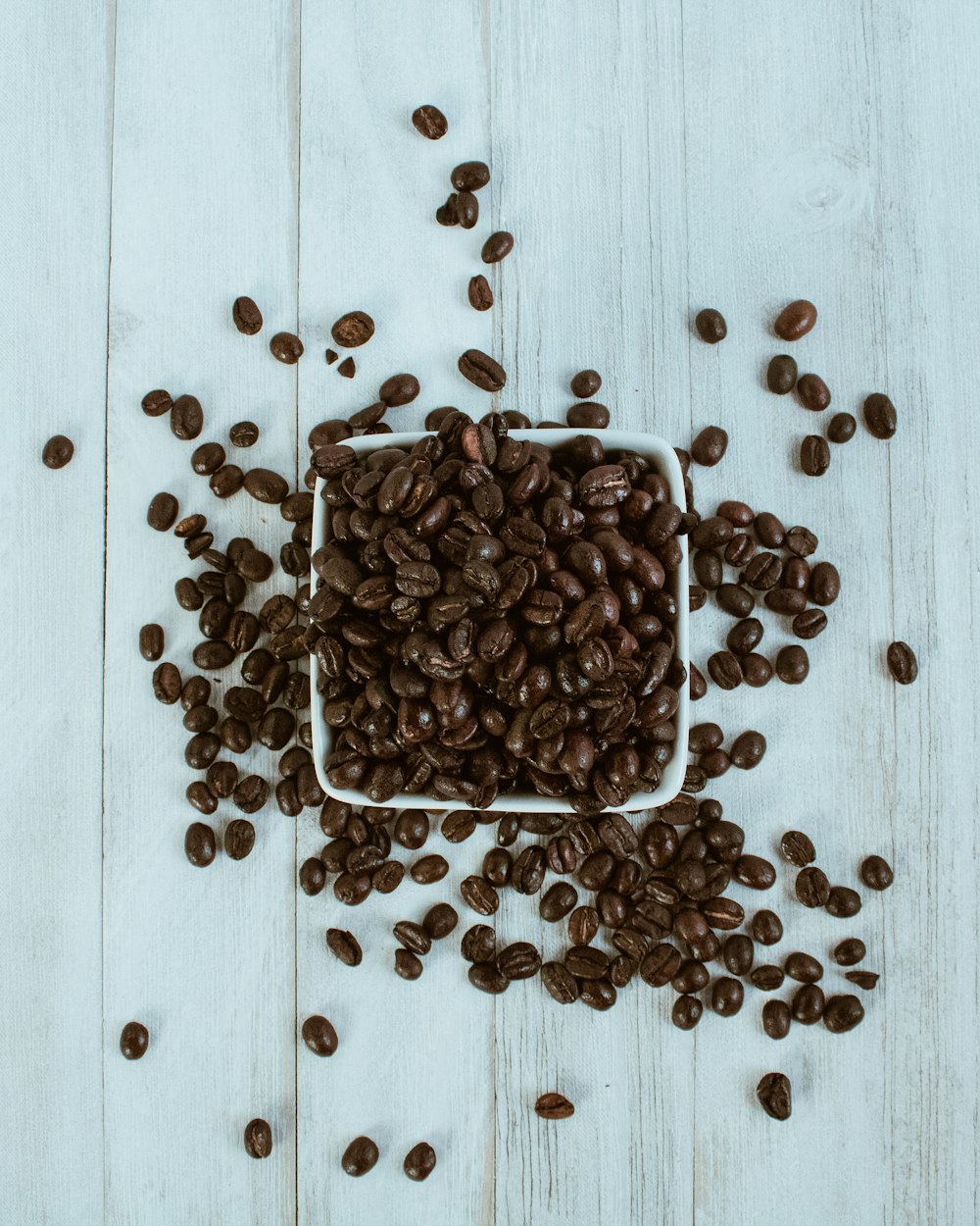 braune Kaffeebohnen auf weißem Holztisch