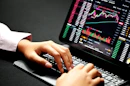 A person analyzing trading charts on multiple screens.