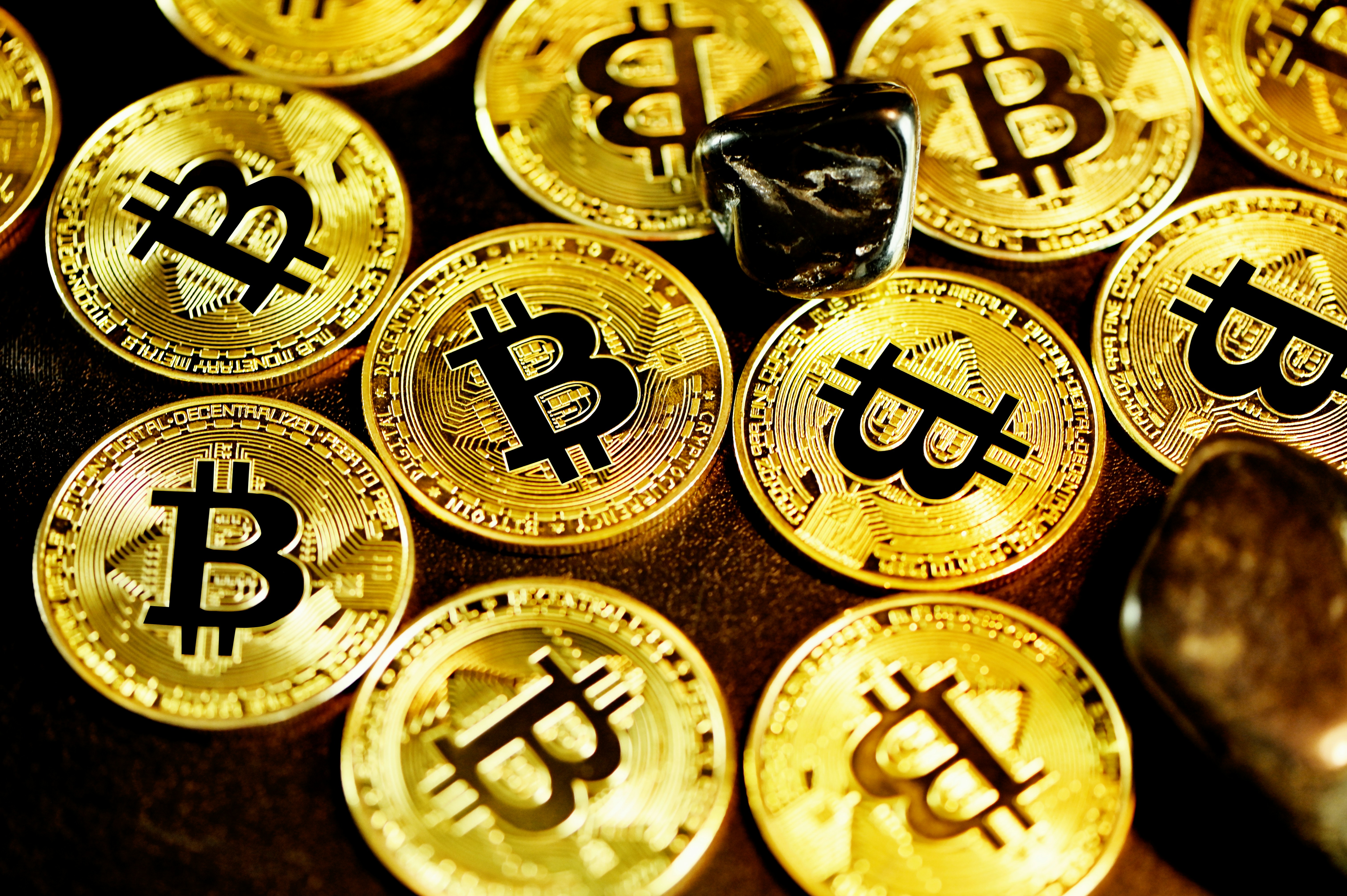 Smooth black stones and Bitcoins scattered across a flat surface.