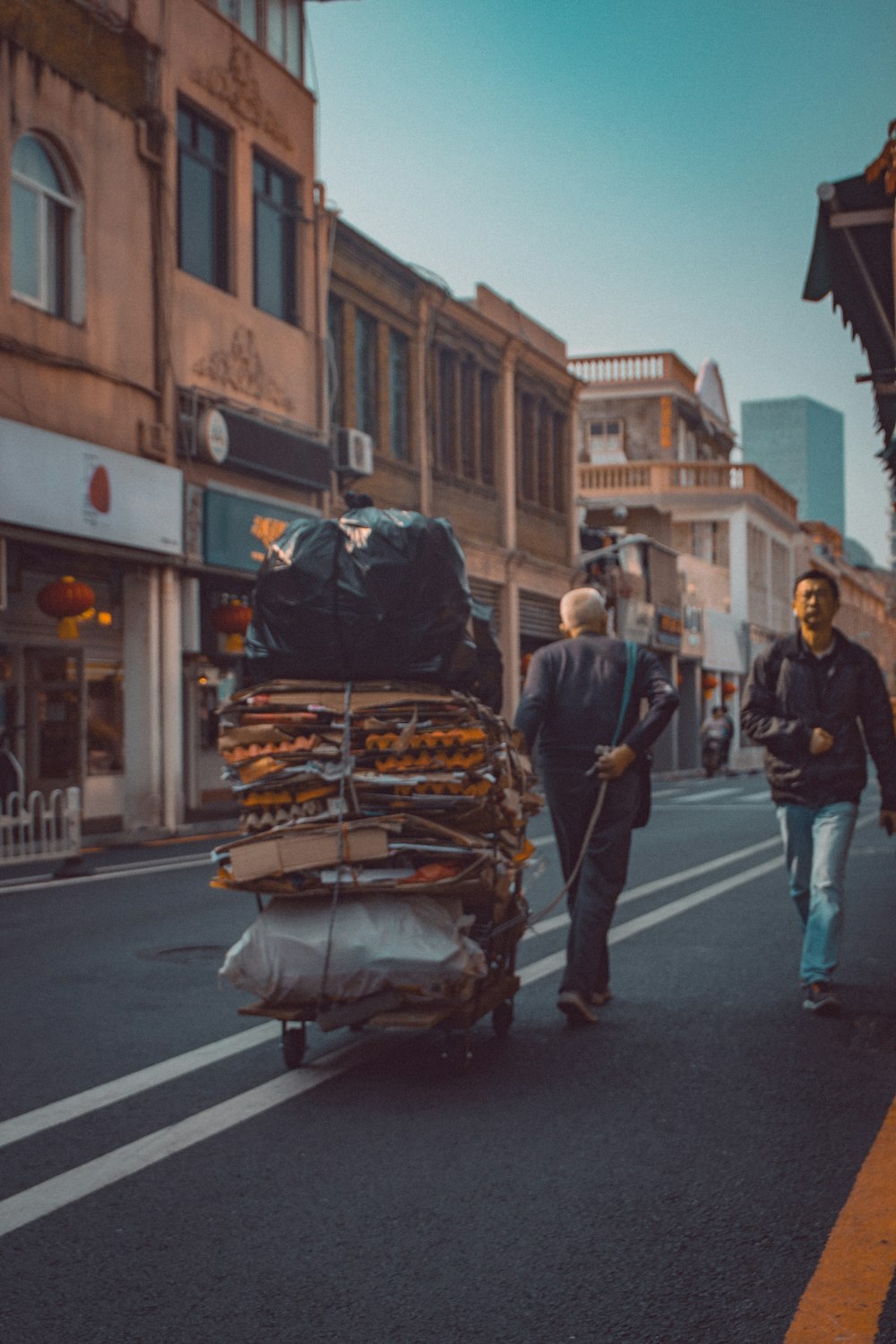 people in a street with cars and buildings in the distance