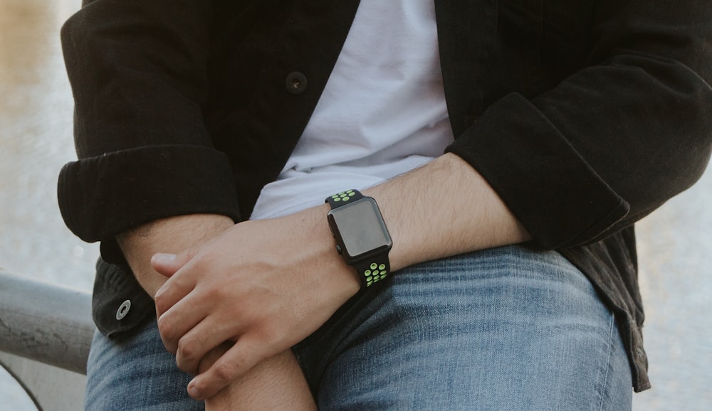 person wearing silver aluminum case apple watch with green sport band