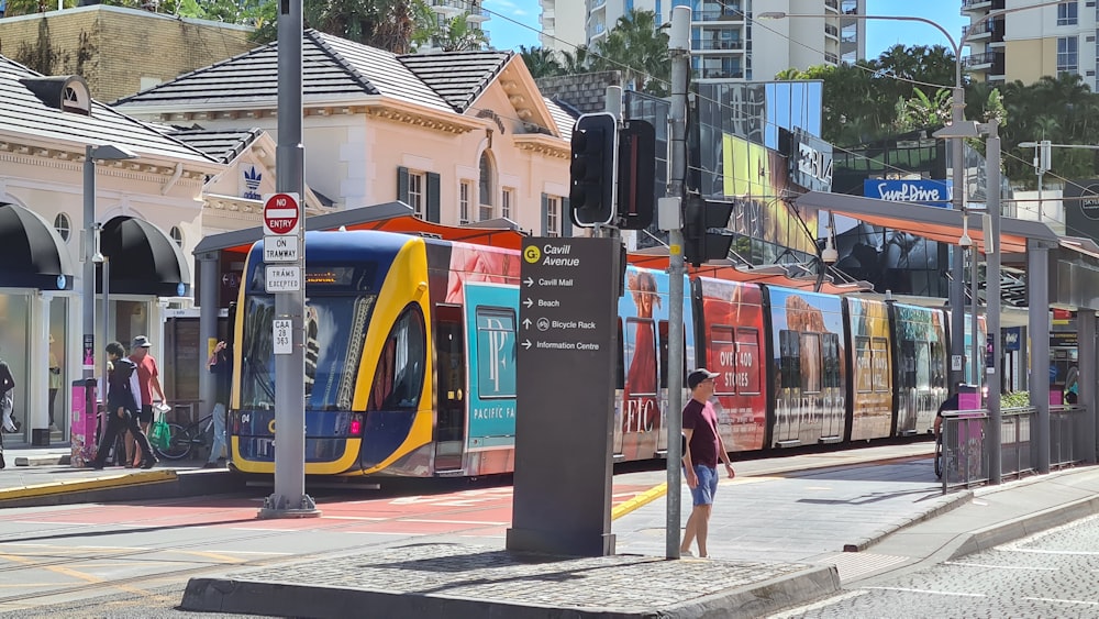 man in red jacket standing beside red and yellow train during daytime